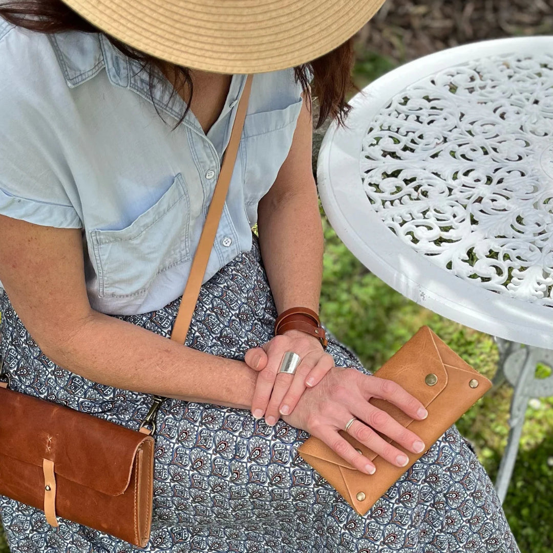 Person holding a brown leather wallet with a white table and green grass in the background