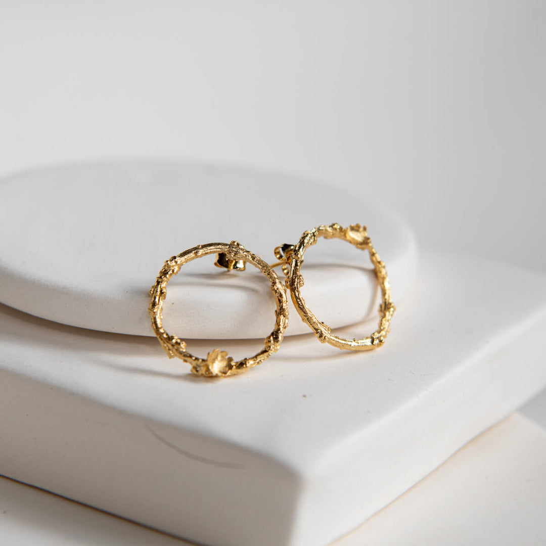 Gold hoop earrings on a white ceramic plate