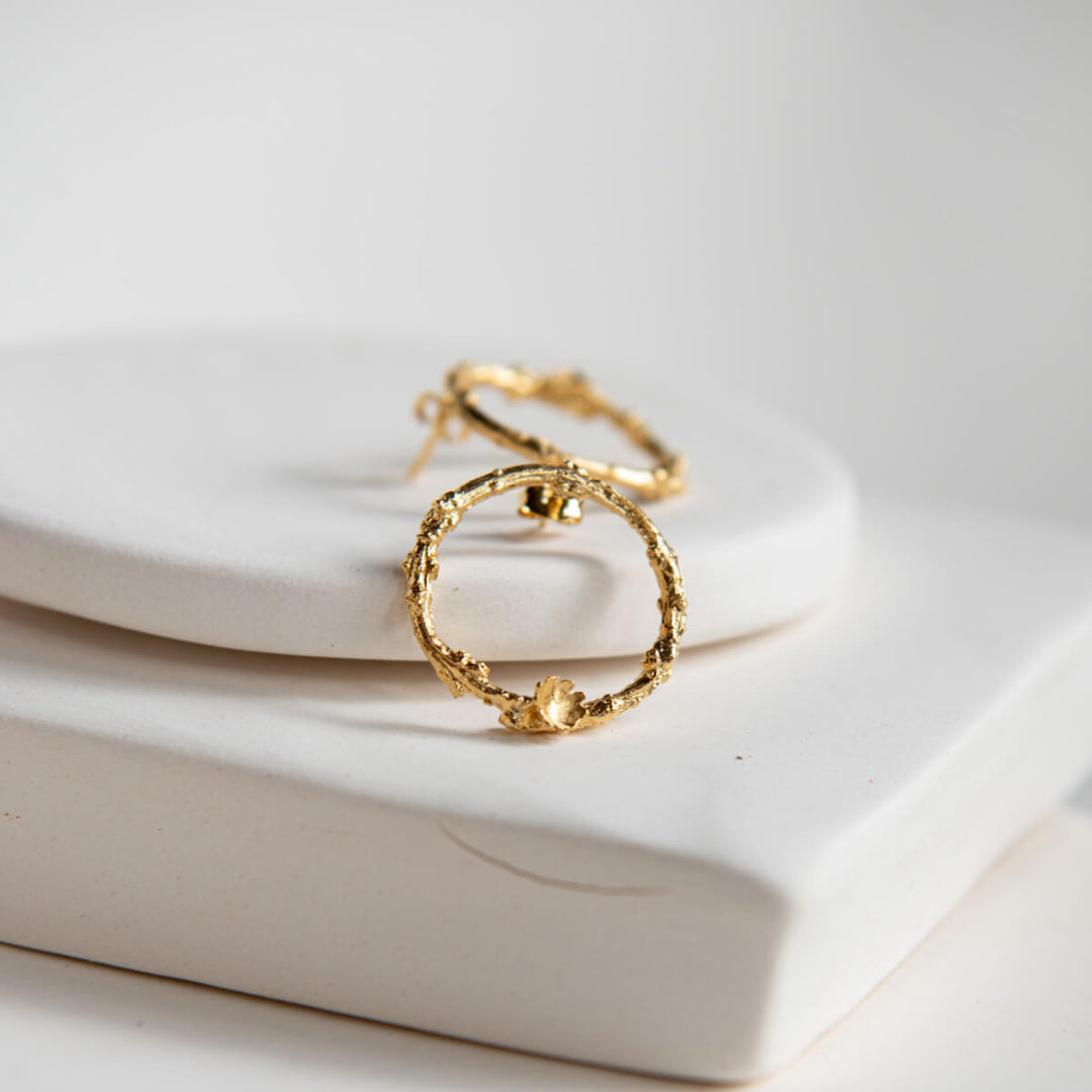 Gold hoop earring on a white ceramic dish