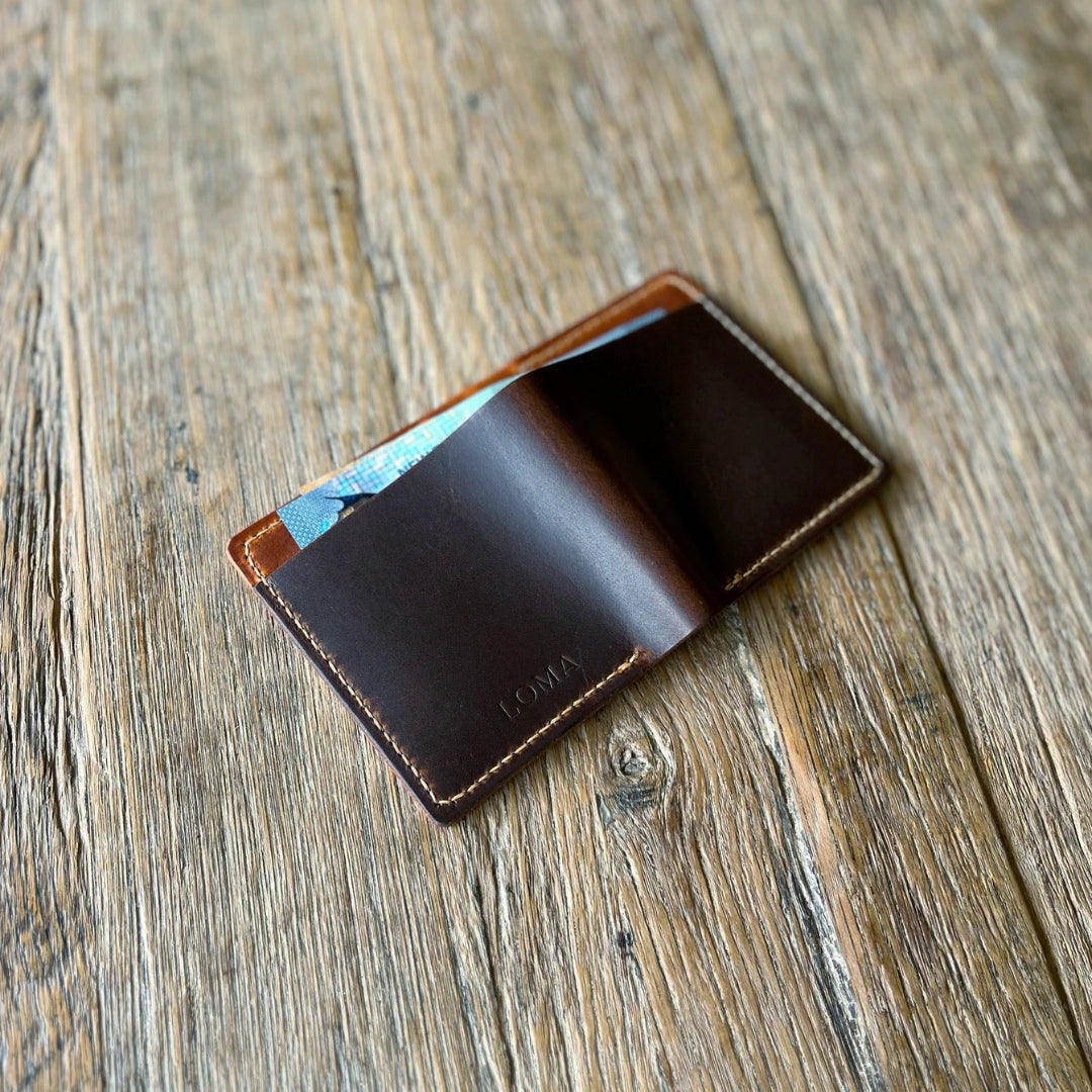 Brown leather wallet showing cash on a wooden surface
