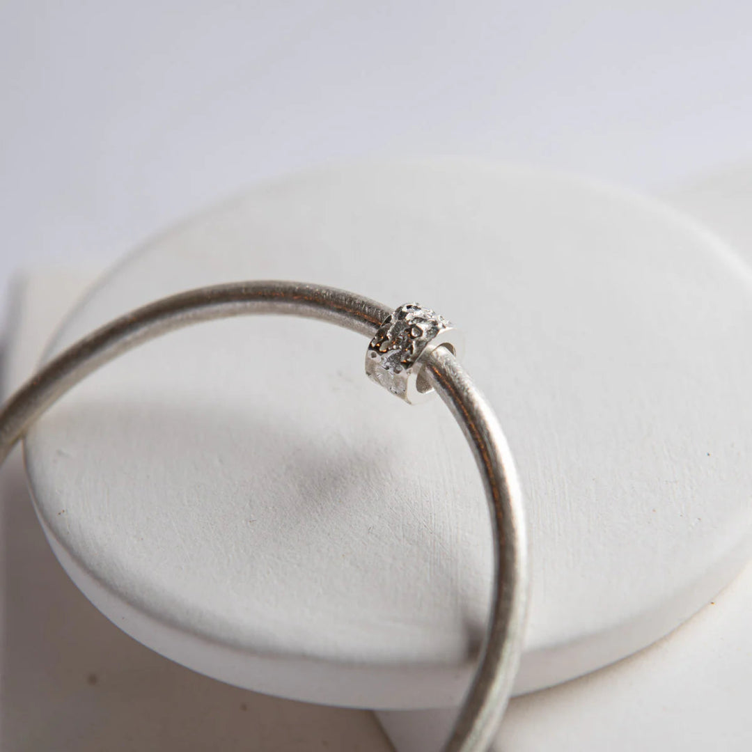 Silver bracelet with a clasp on a white surface