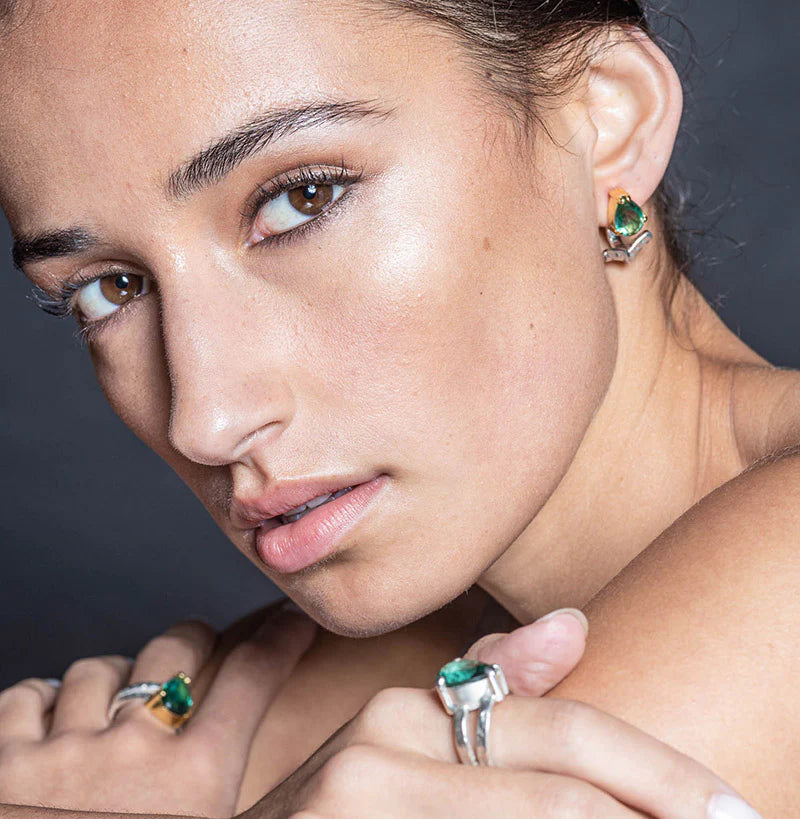 Close-up of a woman wearing emerald jewelry against a dark background