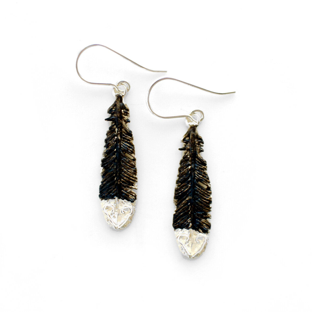 Pair of black and white painted silver Huia feather earrings on a white background background