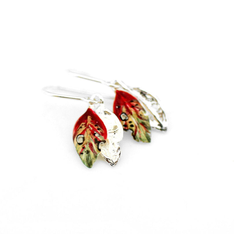 Pair of earrings with red and green leaf-like design on a white background