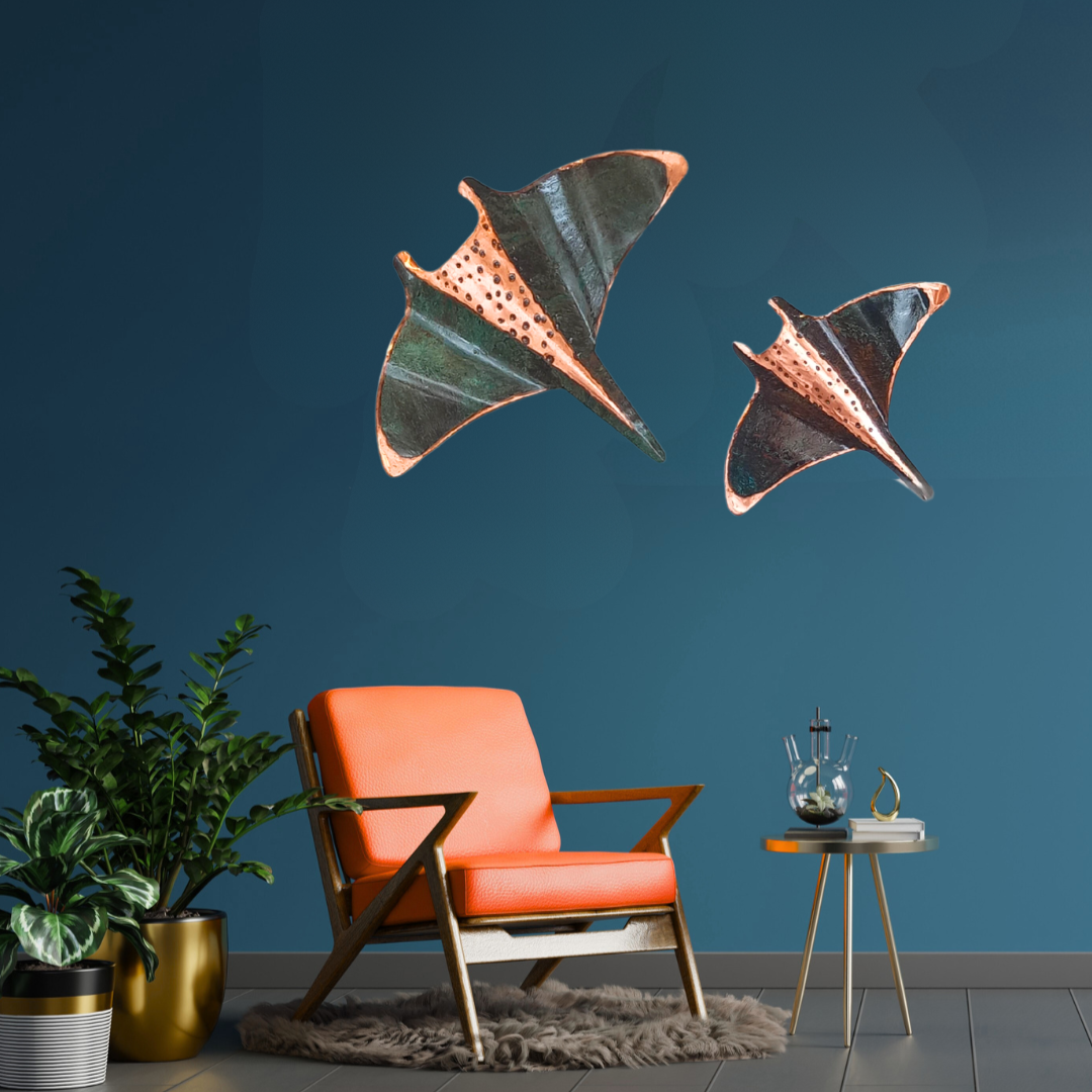 Modern living room with orange chair, plant, and decorative copper wall manta rays against a blue wall.